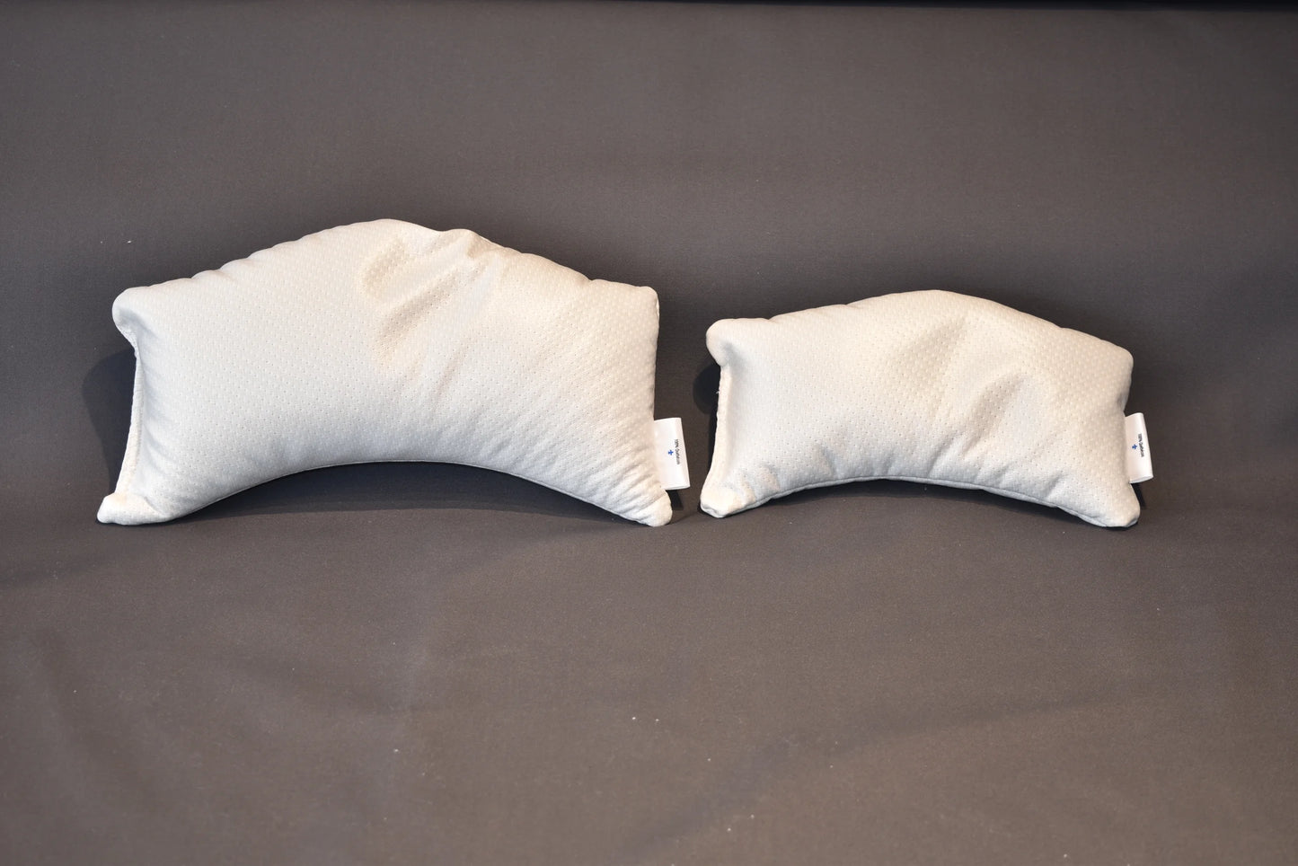 Coussin demi-lune Cause et Couture en tissu blanc, formats Standard et XL posés à plat sur fond gris
