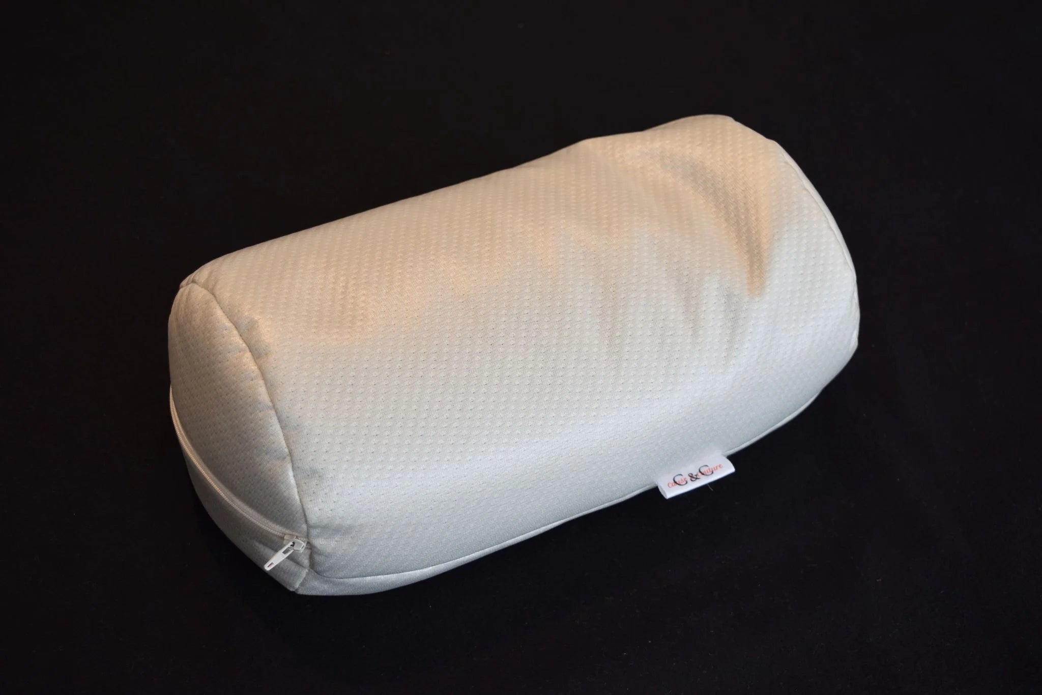 Traversin de massage Cause et Couture en tissu blanc, vue de trois quarts sur fond sombre