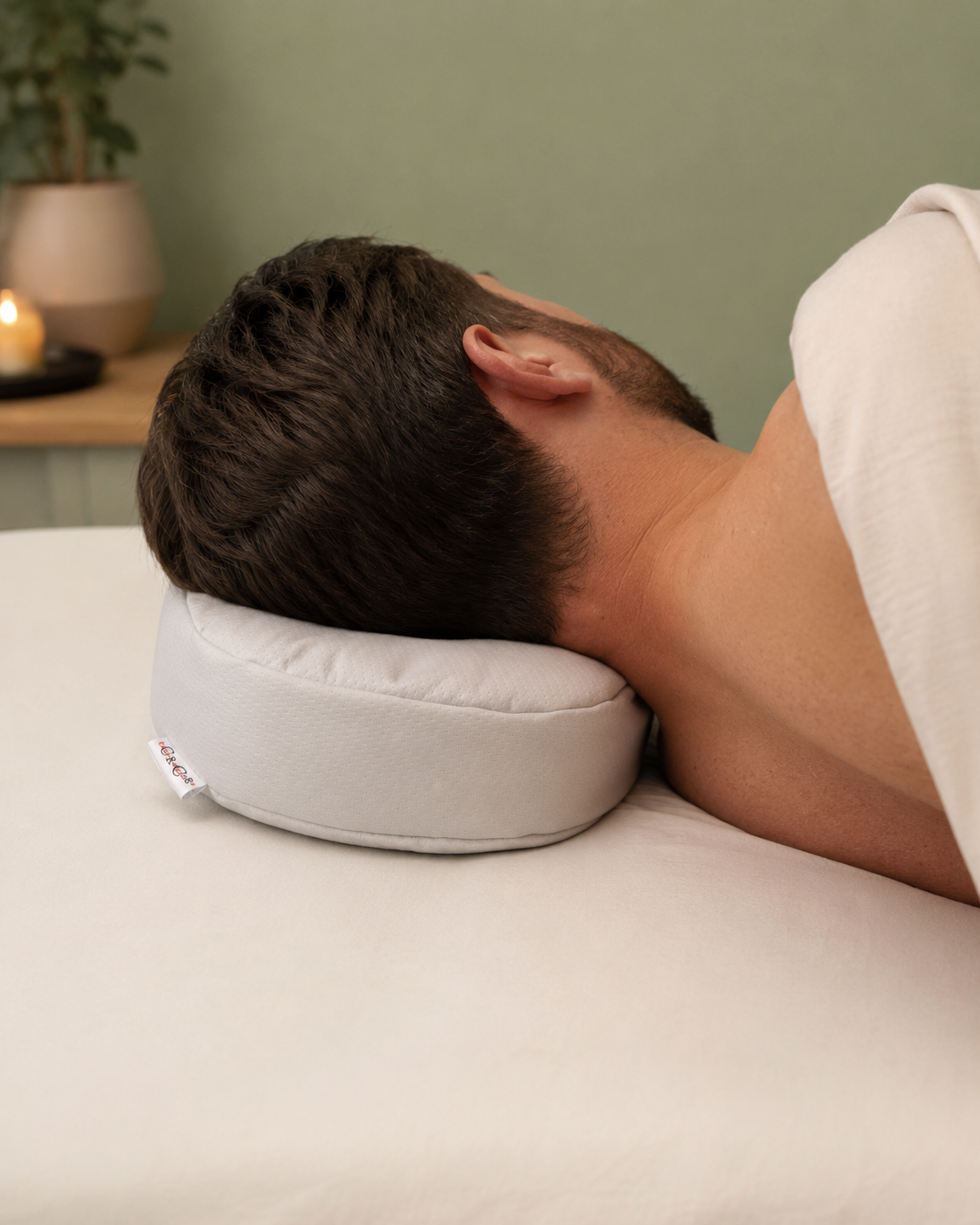 Client allongé sur une table de massage, tête reposant sur l'oreiller fraise en tissu hydrofuge gris