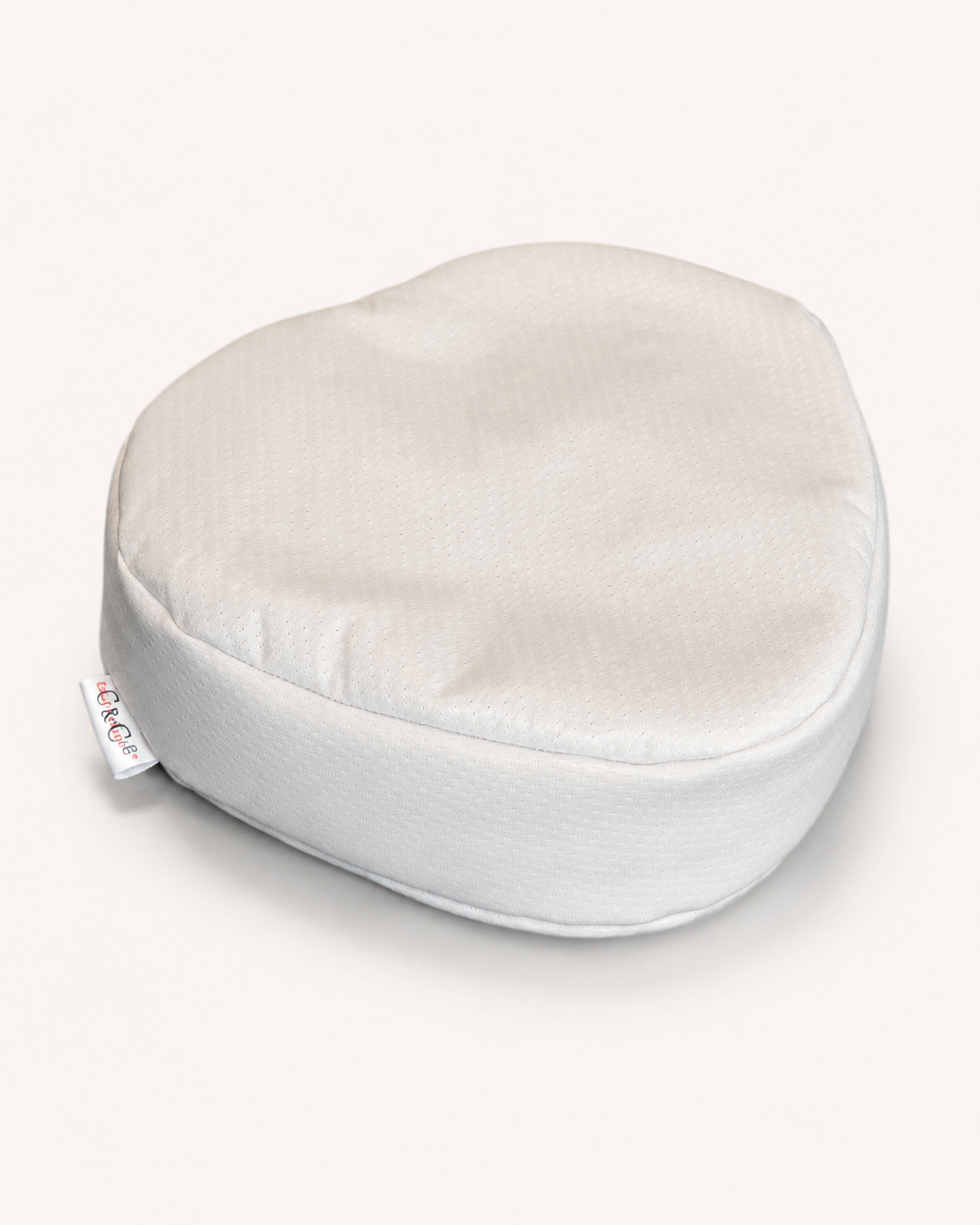 Oreiller fraise aux écailles de sarrasin biologique, forme arrondie en tissu blanc, vue de trois quarts sur fond crème