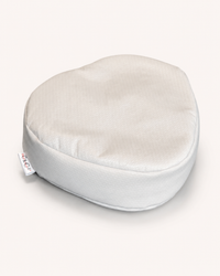 Oreiller fraise aux écailles de sarrasin biologique, forme arrondie en tissu blanc, vue de trois quarts sur fond crème
