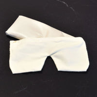 Housse en flanelle blanche par dessus un coussin repose-yeux sur fond sombre
